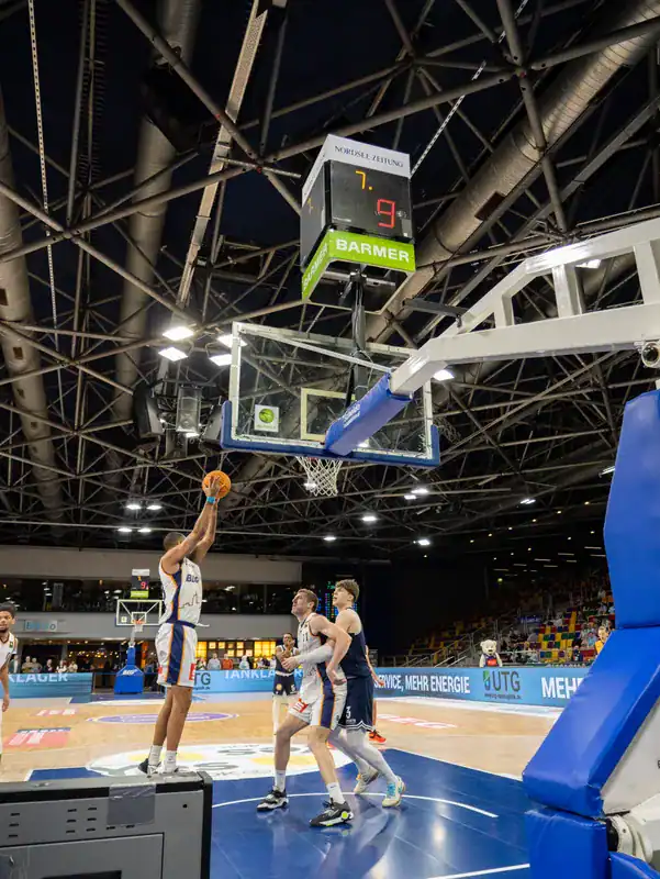 Basketballspieler im weißen Trikot bei einer Aktion direkt unter dem Korb.