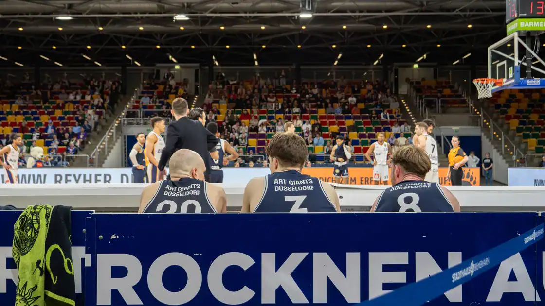 Blick von der Mannschaftsbank auf das Basketballspiel und die Tribüne.