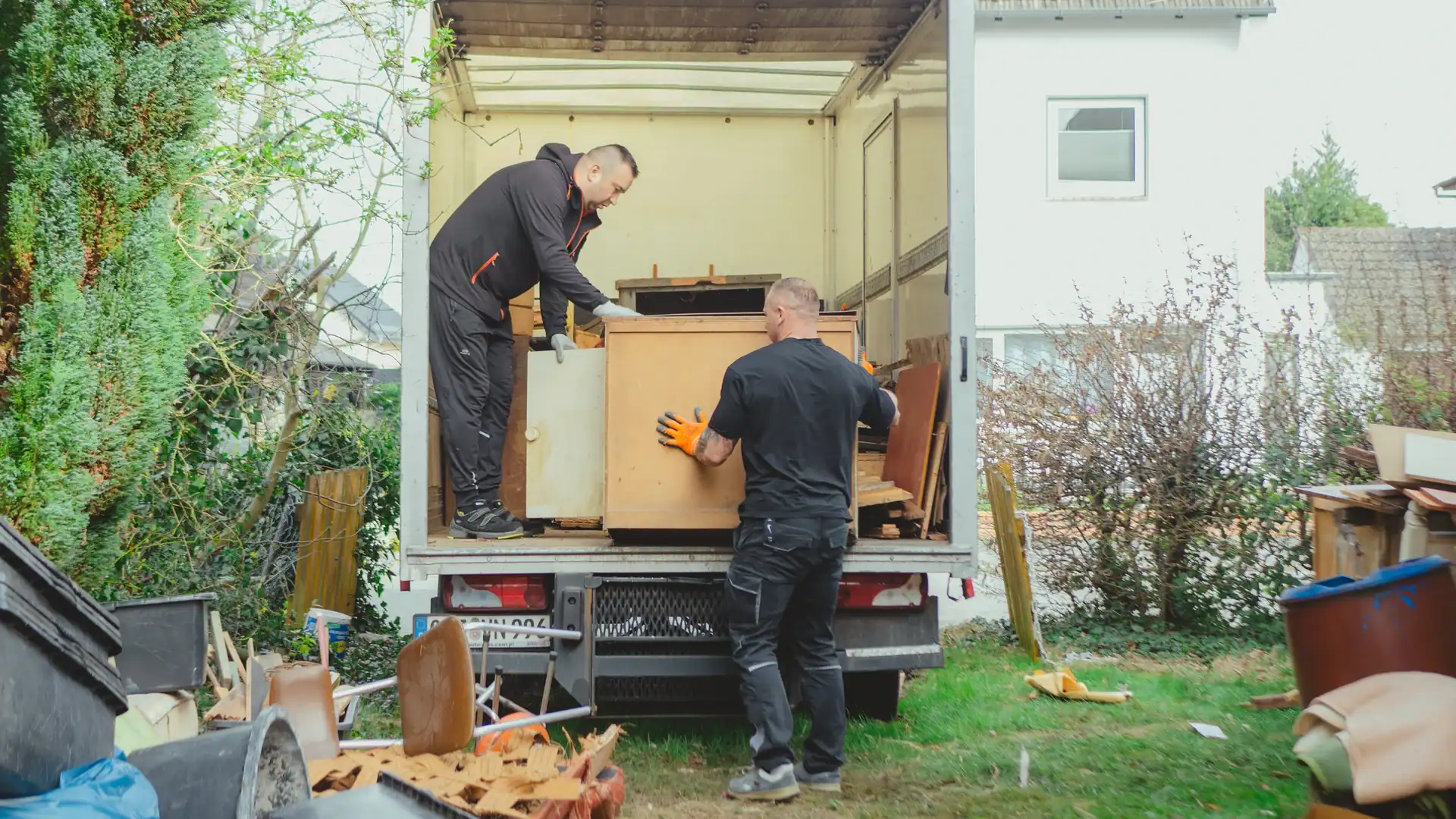 Zwei Mitarbeiter verladen ein Möbelstück in einen Transporter